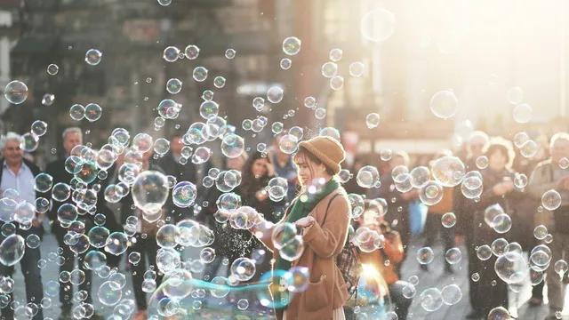 A person surrounded by soap bubbles in a street.