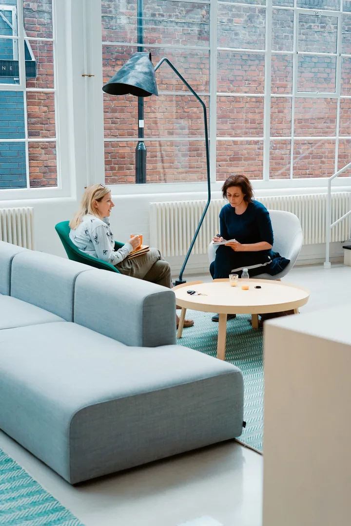 Two people sitting opposite one another in a bright room.